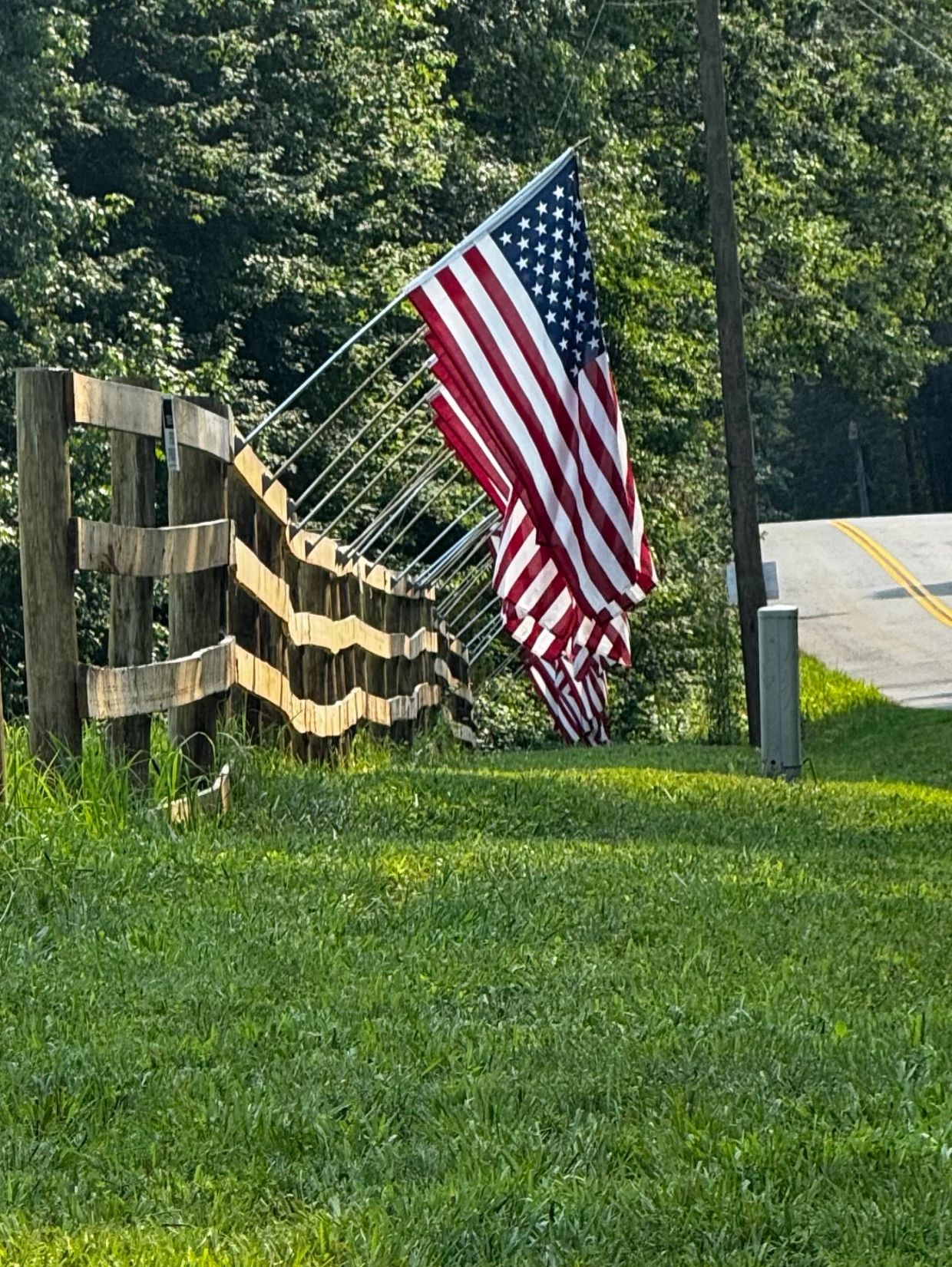 Row of American flags along a wooden fence.