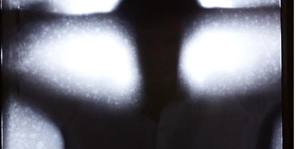 A shadowy figure behind a frosted glass window.