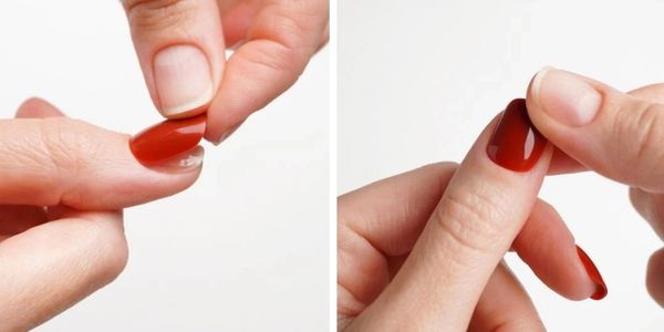 Applying and adjusting red press-on nails on fingertips.