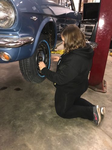 Kimberly installing tires on a 1966 Ford Mustang.