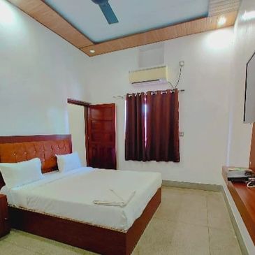A modern bedroom with a double bed, TV, and air conditioner.
