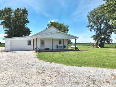 Small white house with a porch and garage on a sunny day.