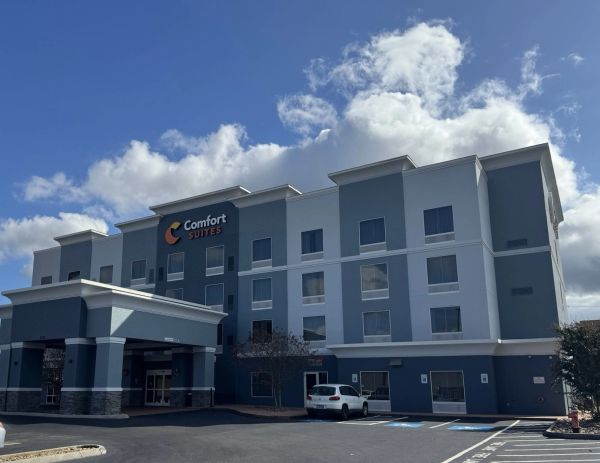 Exterior view of a Comfort Suites hotel building under a partly cloudy sky.