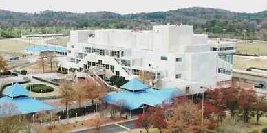 Large modern building with blue-roofed gazebos and autumn trees.