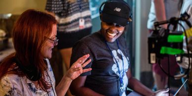 Two women smiling and engaging in a lively conversation indoors.