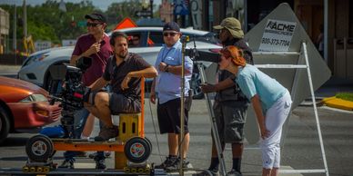 Film crew working with camera equipment on a city street.