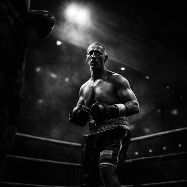 Boxer in a dark ring with dramatic lighting.