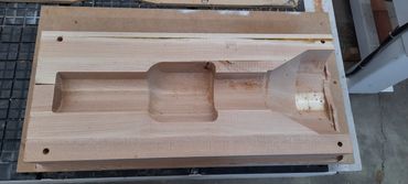 Wooden mold carved with various shapes for industrial purposes.