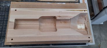 Wooden mold carved with various shapes for industrial purposes.