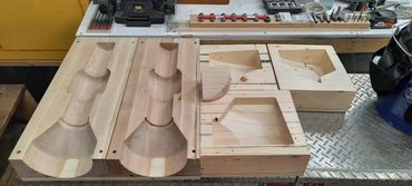 Wooden molds and patterns for shaping or casting on a workbench in a workshop.