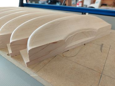 Smoothly carved wooden handles lined up on a workbench.