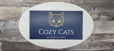 Sign for Cozy Cats boutique cat hotel with cat illustration.