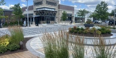 Outdoor shopping area with greenery and a restaurant named Firebirds.