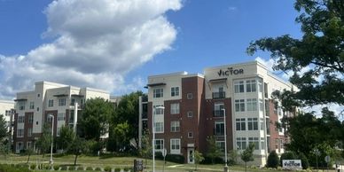 Modern apartment buildings under a partly cloudy sky with greenery around.