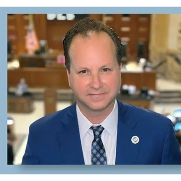 Professional man in a blue suit smiling in an official setting.