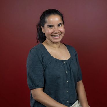 A young college girl, with her hair in a pony tail, smiling at the camera for her LinkedIn headshot.