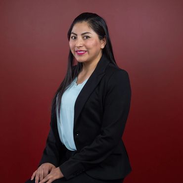 A young lady wearing light blue blouse and black blazer. Sitting for a headshot.