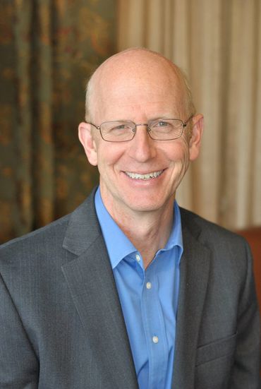 man smiling in his office for a headshot