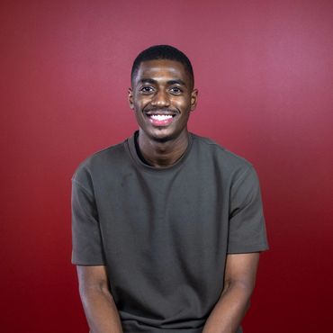 Headshot of a smiling young African American man in a green short-sleeved shirt.