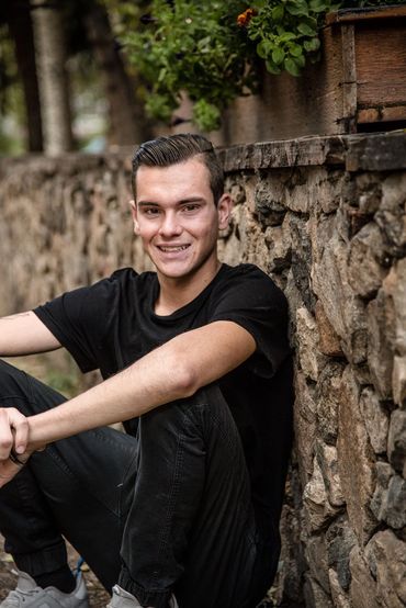 young man in the mountain town of Georgetown sitting and leaning against a rock wall