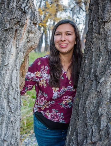 A High School senior young lady standing between 2 tree trunks at McKay Lake in Westminster