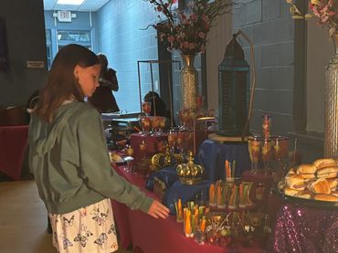 A girl observes a colorful buffet table with drinks and food.