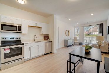 Modern kitchen and living area with light wood flooring.