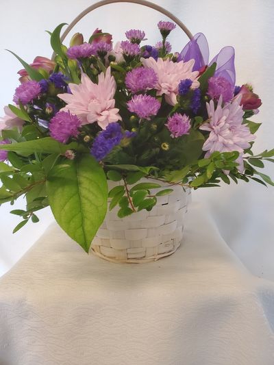A basket of purple flowers with seasonal greens.