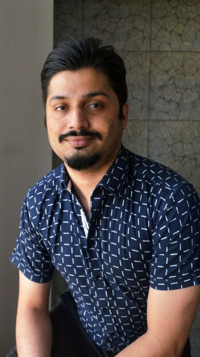 Portrait of a smiling man in a patterned navy shirt.