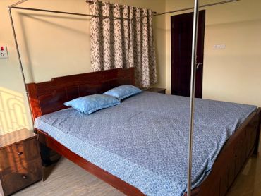 A wooden bed with blue bedsheet and pillows in a cozy room.