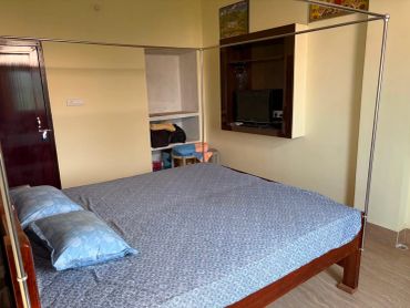A simple bedroom with a wooden bed and small TV.