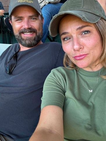Smiling couple wearing casual hats taking a close-up selfie.