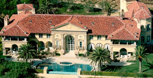 Mediterranean-style mansion with red tile roof and large pool.