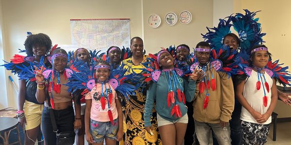 Group of youth smiles in feathered costumes while participating in the Dream Big Academy