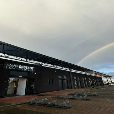 Een foto van een gebouw van een sportschool met een regenboog in de lucht.