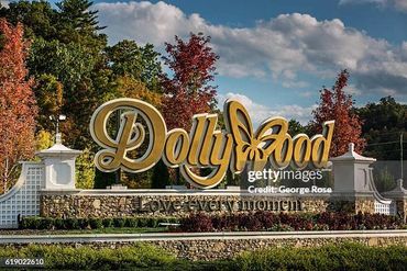 Entrance sign of Dollywood theme park with autumn trees in the background.