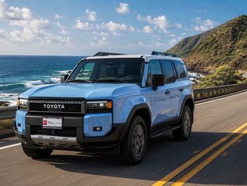 Blue Toyota SUV driving along a coastal road.