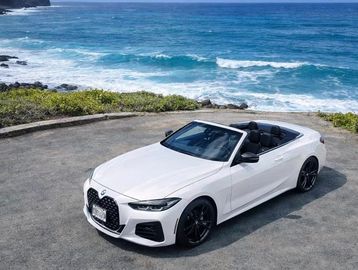 White BMW convertible parked near the ocean.