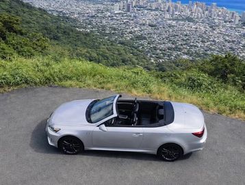 Silver convertible car parked on a mountain road.