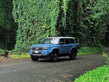 Blue Toyota SUV on a forest road.