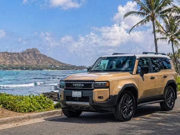 Toyota SUV parked near the beach with a mountain backdrop.