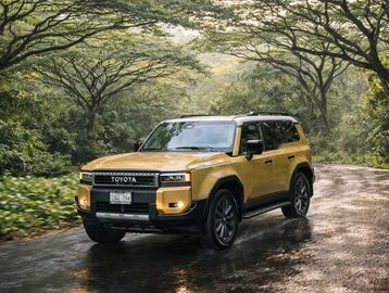 Yellow Toyota SUV driving on a wet forest road.