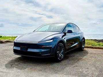 A sleek black electric car parked by the seaside.
