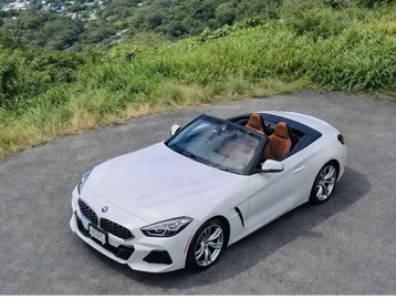 White BMW convertible parked near greenery.