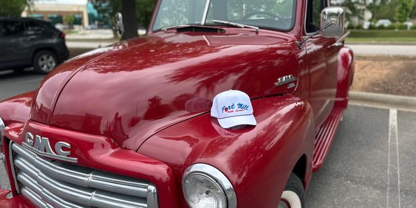 Red vintage GMC truck with a white hat on the hood.