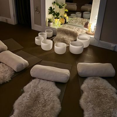 A cozy meditation space with cushions, mats, and crystal singing bowls arranged.