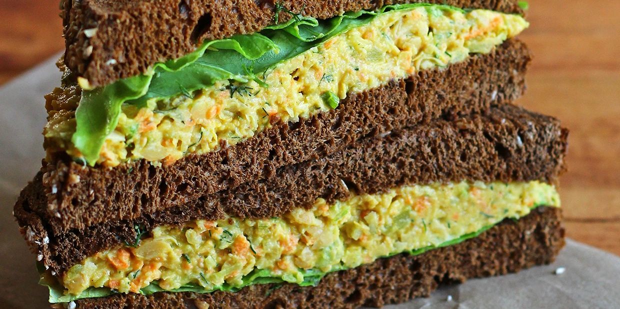 Close-up of a sandwich with dark bread and vegetable filling.