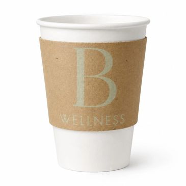 White paper coffee cup with a brown sleeve labeled 'B Wellness'.