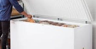 man reaching into a chest freezer.