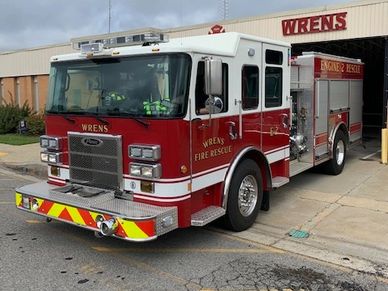 A red and white fire rescue truck parked outside a fire station.